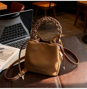 Detail of caramel PU leather bucket bag with woven handle and adjustable strap