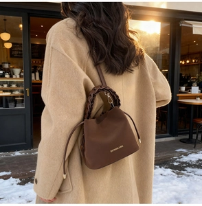 Detail of dark brown PU leather bucket bag featuring woven handle and drawstring design