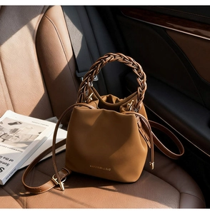 Detail of brown PU leather bucket bag with woven handle on a car seat