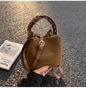 Detail of brown PU leather bucket bag with woven handle and gold hardware on street