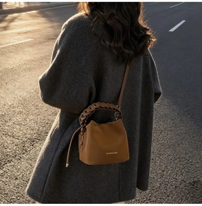Brown PU leather bucket bag with woven handle shown in sunset street photography
