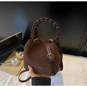 Detail of soft brown PU leather bucket bag featuring a thick woven handle and gold hardware