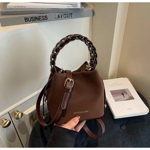 Detail of soft PU leather bucket bag featuring a thick braided handle and golden logo