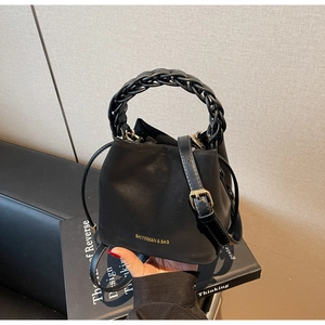 Close-up of black PU leather bucket bag featuring woven handle and drawstring closure