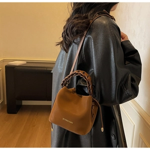 Detailed macro view of the caramel brown PU leather bucket bag with woven handle and drawstring