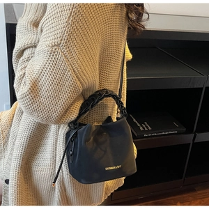 Detail of black PU leather bucket bag with thick braided handle and drawstring closure