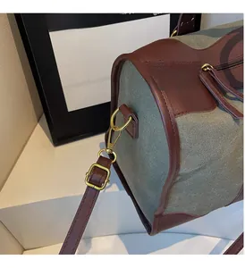 Close-up of olive green canvas tote with brown leather trim and golden metal buckle