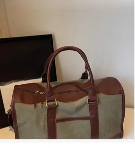 Detail of olive canvas tote with brown leather handles and golden metal hardware zipper