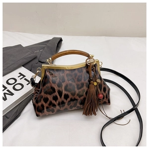 Détail du sac léopard avec poignée en bois, cadre doré et pendentif à franges