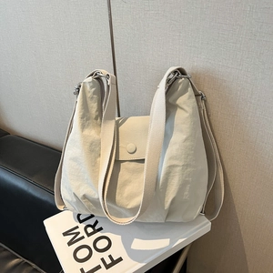 Minimalistische beige Nylon Hobo-Tasche für Damen mit breitem Gurt auf weißem Buch
