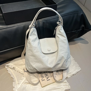 Minimalistische hellgraue Halbmond-Schultertasche mit verstellbarem Gurt auf Tischtuch