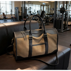 Detail of khaki canvas tote with black leather trim and straps on a gym bench
