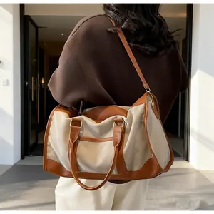 Detail view of contrast canvas tote bag featuring premium leather trim and metal hardware