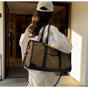 Outdoor back view of large canvas tote bag with contrast leather trim and shoulder strap