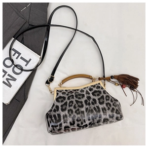 Détail du sac léopard avec poignée en bois, fermoir doré et pendentif à pompon décoratif