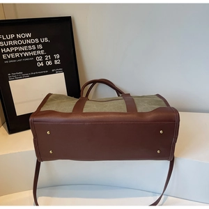 Detailed base view of canvas tote featuring protective gold metal feet and leather strap