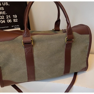 Close-up of military green heavy canvas travel bag with premium dark brown leather handles
