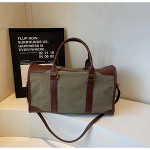 Detail of army green canvas tote bag showing dark brown leather handles and gold hardware