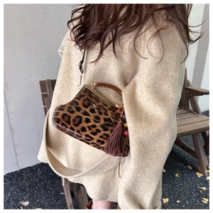 Détail du sac à bandoulière léopard avec poignée en bois et décor de pompons élégants