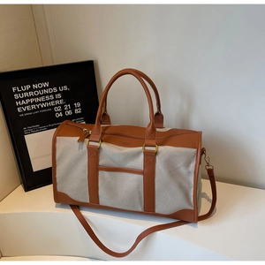 Detail of canvas duffel bag with brown leather accents and adjustable shoulder strap