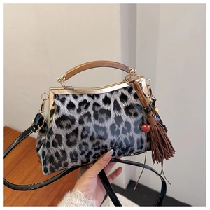 Détail d'un sac à main léopard en cuir verni brillant avec poignée en résine et pompons