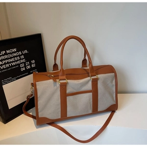 Detail of canvas tote bag with brown leather handles and a detachable shoulder strap