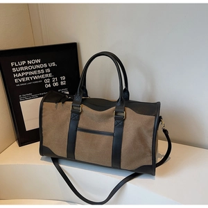 Close-up of canvas travel tote featuring leather trim, sturdy handles and metal hardware