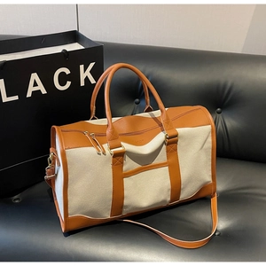 Detail of canvas tote with brown leather trim and shoulder strap on a black sofa