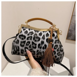 Détail du sac léopard avec poignée en bois et pompon à franges élégant