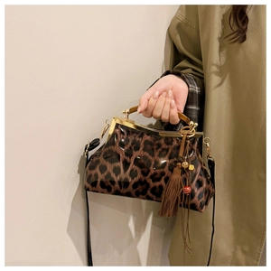 Détail du sac léopard en cuir verni avec poignée métallique et pompon décoratif