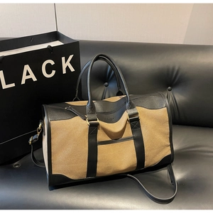 Detail of the large canvas duffel bag with black leather trim and detachable shoulder strap