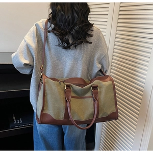 Detail of olive canvas tote bag with brown leather trim shown on shoulder in home setting