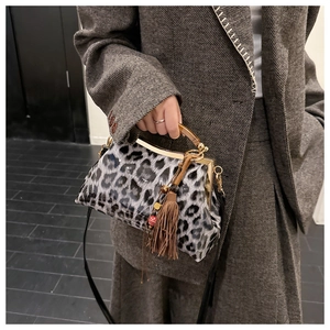 Détail du sac léopard avec poignée en écaille et breloque à pompon élégante