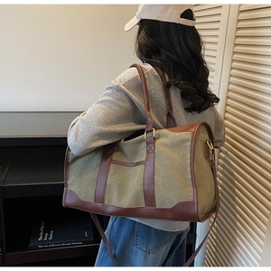 Lifestyle view of a large olive canvas travel tote bag with brown leather accents