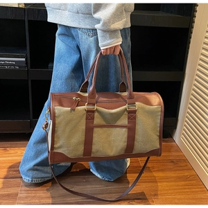 Detail of army green canvas travel duffel bag with brown leather handles and hardware