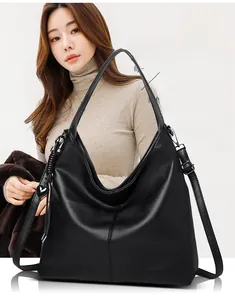 Close-up of black leather tote bag with vertical stitching and heart-shaped pendant detail