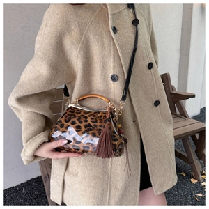Détail d'un sac en cuir verni léopard avec poignée ambre et pendentif à pampilles