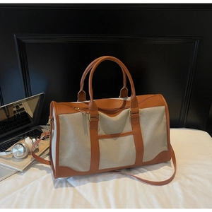 Macro view of canvas travel tote bag featuring brown leather trim and gold metal hardware