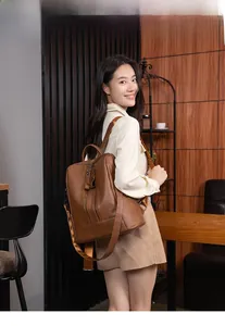 Detail of brown litchi leather backpack with double zippers and fabric straps
