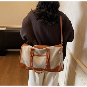Model showing large canvas tote bag with brown leather trim in a cozy indoor setting