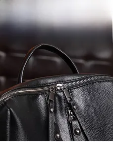Detail of silver dual-way metal zippers and litchi grain leather on a black backpack