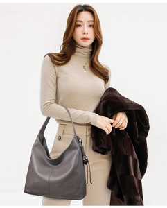 Detail view of dark grey pebbled leather hobo bag with wide strap and decorative pendant