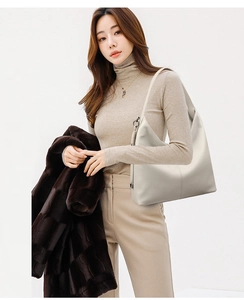 Close-up of minimalist off-white leather hobo bag featuring wide shoulder strap detail