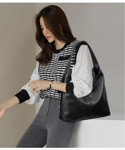 Detail of black pebbled leather hobo bag with wide shoulder strap on a model