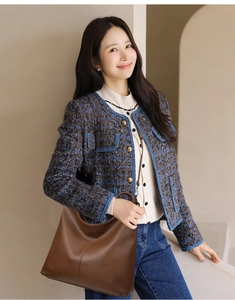 Close-up of a large brown pebbled leather tote bag with a stylish tweed jacket and jeans