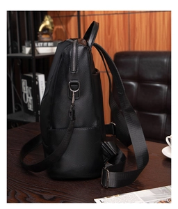 Close-up of black lychee grain leather backpack showing side pocket and nylon straps