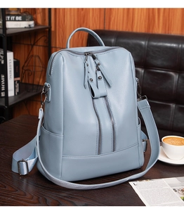 Close-up of light blue pebble leather backpack on a desk with dual vertical zippers