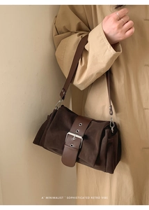Détail d'un sac plissé vintage marron foncé porté avec un trench-coat kaki élégant