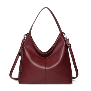 Deep red pebbled leather hobo handbag with wide strap and tassel detail on white background