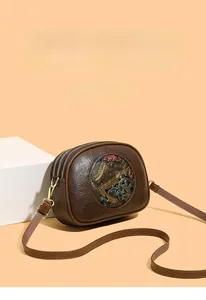 Detail view of vintage brown crossbody bag with embossed floral art and dual zippers
